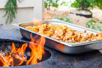 Grilled corn and potatoes in a metal tray on an outdoor fire pit, vegetarian barbecue food concept
