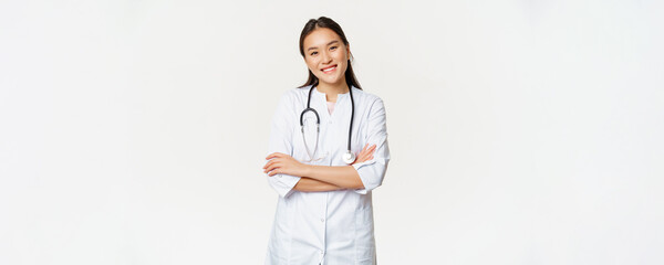 Asian female doctor, physician in medical uniform with stethoscope, cross arms on chest, smiling and looking like professional, white background
