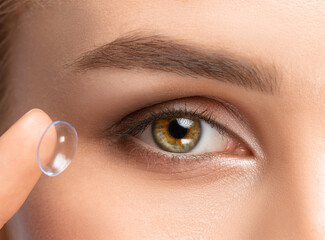 Beautiful woman holds contact lens on her finger. Eye care and the choice between the means to...