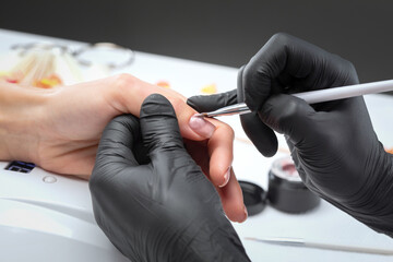 Coating nails with gel polish in the beauty salon. Professional care for hands.