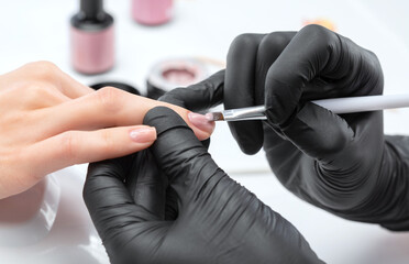 Coating nails with gel polish in the beauty salon. Professional care for hands.