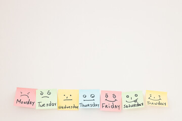 Day of week and face expression. Colored stickers on white wall