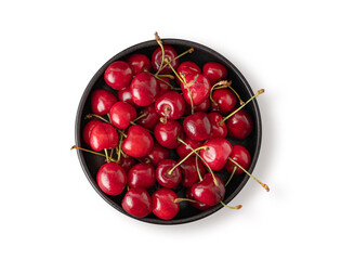 Fresh cherries in a black bowl on a white isolated  background. Top view and copy space