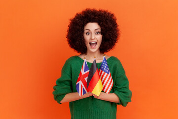 Excited astonished woman with Afro hairstyle wearing green casual style sweater standing holding in...
