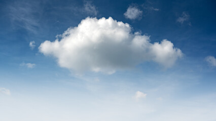 Blue sky and small fluffy single cloud illuminated by the day sun light. Nature background