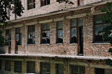 The wall of an old abandoned brick building with broken windows. Facade of destroyed building.
