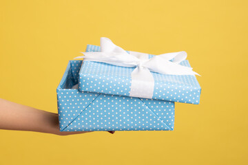 Closeup of woman hands holding wrapped blue gift box with stripe, arms giving birthday present to...