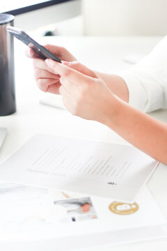 Woman holding phone on office desk