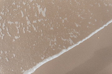 Sandy beach near the ocean and the wave, top view.
