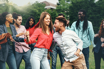 Multi-ethnic group of young men and women carefree dancing in the nature - multiracial lifestyle diversity concept of young people culture and weekend leisure activities