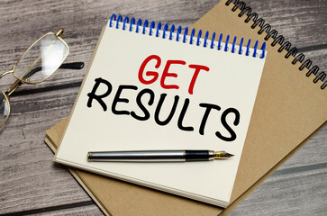 get results on notebook and pen on wooden background