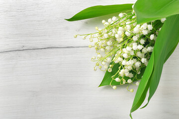 Bouquet of lilies of the valley on a light gray wooden background.