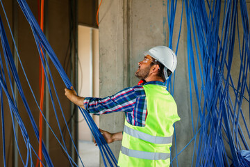 A skilled electrician in construction checking cables for building electric network.