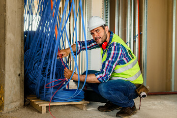 A skilled electrician in construction checking cables for building electric network.