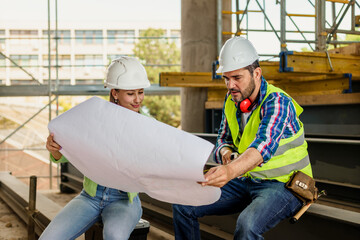 Woman architect explaining blueprint to supervisor at construction site. Engineer talking to contractor.