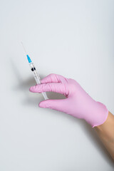 A hand in a pink rubber glove with a medical syringe