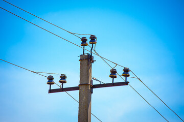 A power line pole in close-up against a blue sky background