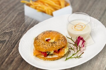 Philly cheesesteak sandwich made with cheese and onions with french fries on a wooden board