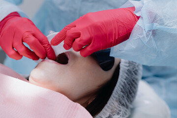 The dentist fixes the woman's mouth before the procedure. Dentistry.