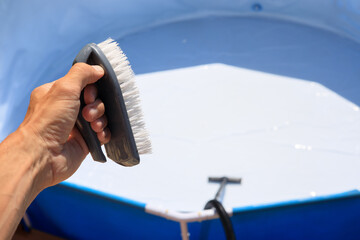 Washing the pool for the new summer bathing season using a brush and vacuum cleaner