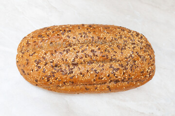 Bread with seeds on the table. Flat lay. Top view. Marble countertop.