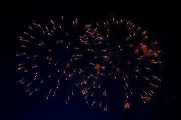 Bright balls of fireworks with orange sparks on the background of the night sky. High quality photo