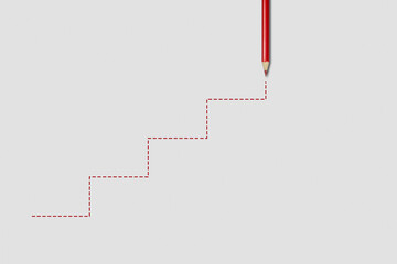 A red pencil draws the stairs on a gray background. Business, education or career concept - achievement of success.