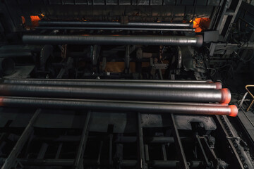 Obraz premium Freshly cast hot cast iron pipes at smelter. Manufacture of pipes for water, gas or oil.