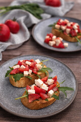 Bruschetta with tomatoes, Feta cheese and arugula on a dark wood table. 