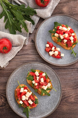 Bruschetta with tomatoes, Feta cheese and arugula on a dark wood table. 
