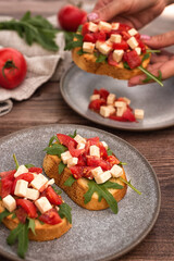 Bruschetta with tomatoes, Feta cheese and arugula on a dark wood table.