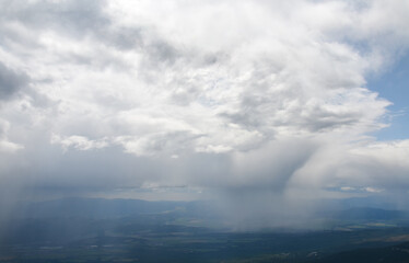 Panoramic landscape of misty rain and storm clouds over the valley between the mountains