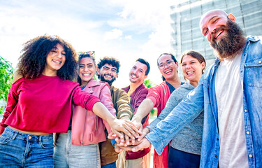 portrait of happy diverse large group of multicultural friends holding hands making high five stacking them together outdoor. convivial people having fun. friendship, unity, team and lifestyle concept