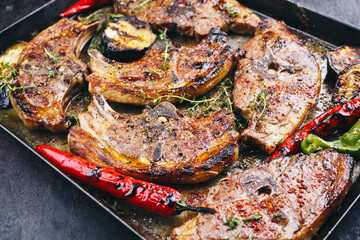 Barbecued lamb saddle back chop steaks with chili and eggplants served as close-up on a rustic metal sheet