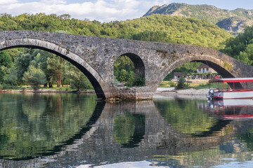 ponte de pedra espelhada no lago Shkodra em Montenegro