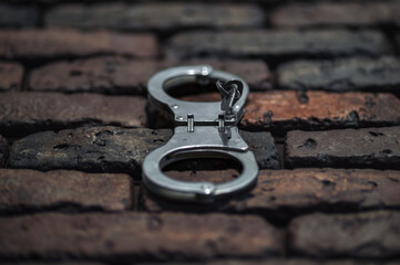 Handcuffs with keys are hanging on a brick wall. Close-up.