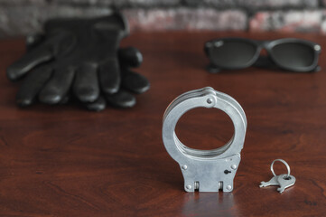 handcuffs with keys, leather gloves and sunglasses on the table.