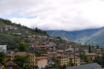 Fototapeta na wymiar Italy: panorama of a village on Lake Garda with the peaks of the Alps covered by clouds