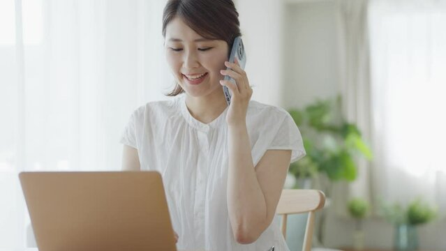パソコンをしながらスマホで電話をするミドル女性