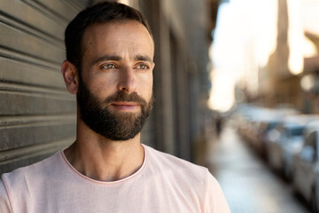 Obraz premium Close up portrait of pensive handsome hispanic man with stylish beard looking away standing on the street, copy space 