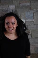 woman in black standing in front of stone wall