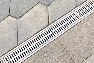 Gutter, drain for rain water on the sidewalk in the park. Drainage systems on paving slabs....