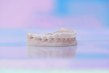 Printed transparent dental cap made of polymer on a light colorful background. Dental splint against bruxism.