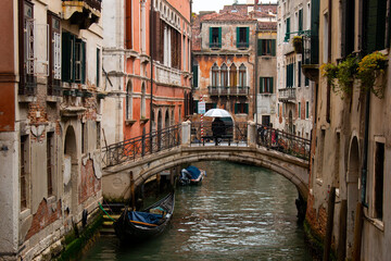 Obraz na płótnie Canvas Venice, Italy, May the 7th 2022: A lonely figure under a huge umbrella on an empty bridge on a rainy morning.