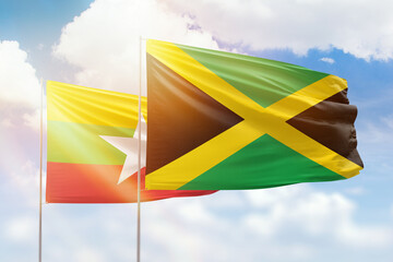 Sunny blue sky and flags of jamaica and myanmar