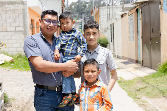 Latin dad with his children outside his house-Hispanic father proud of his children-father of a young family