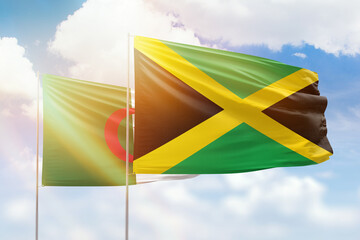 Sunny blue sky and flags of jamaica and algeria