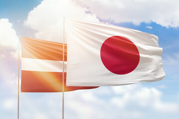 Sunny blue sky and flags of japan and latvia