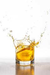 Splash of ice cube on a glass of whiskey, over a white background