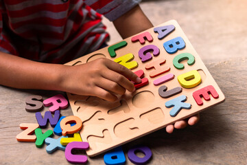 English alphabet made of square wooden. The child's hand grabs the English alphabet to put it in the correct block.